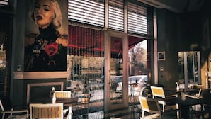 A cozy coffee shop interior with large windows, wooden furniture, and a mural on the wall. - Lova Hotel SPA (Yalova)