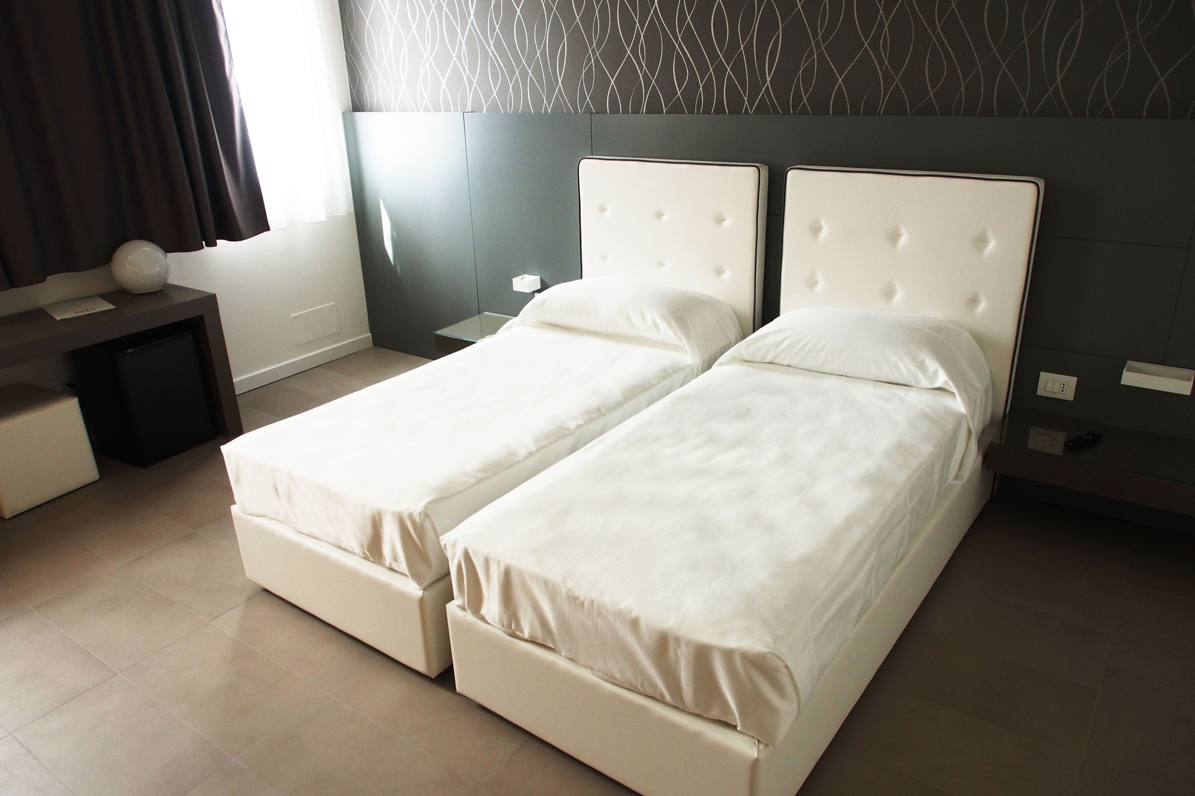 Uma cama de casal com cabeceira, mesa de cabeceira e abajur.