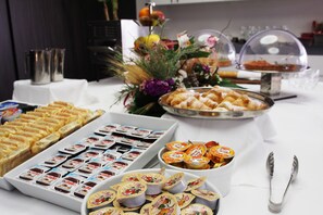 Noutopöytä, jossa on tarjolla monenlaista ruokaa, kuten leivonnaisia, voileipiä ja pakattuja välipaloja.