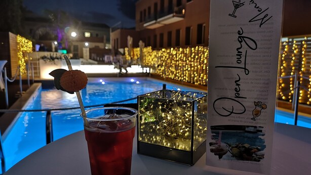 Una mesa con una bebida, un menú y una caja decorativa con luces.