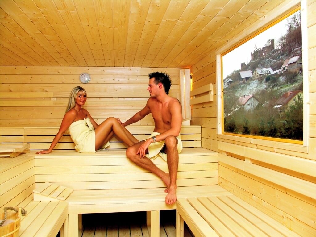 A wooden sauna with benches and a large window.