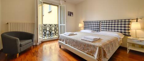 A bedroom with a bed, a chair, a lamp, and a window with curtains.