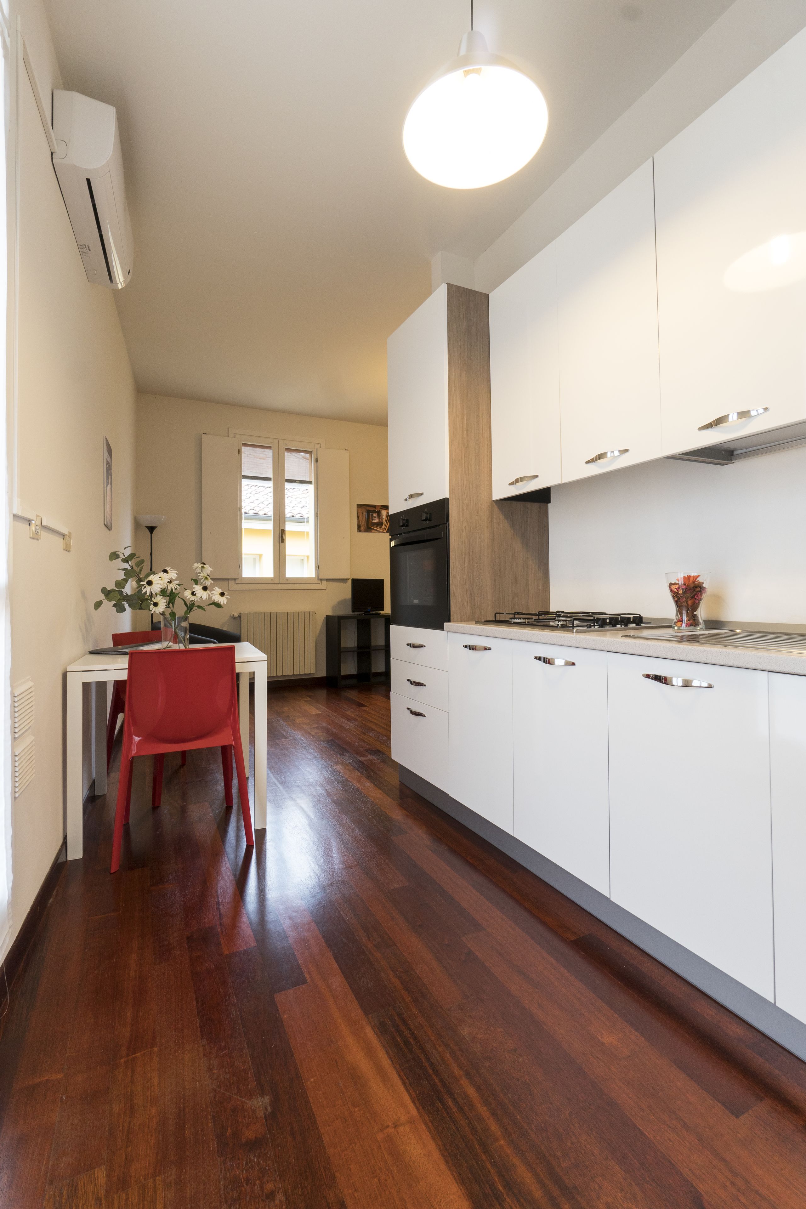 A modern kitchen with white cabinets, a red chair, and a dining table.