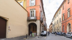 Une rue étroite, bordée de voitures garées et d’immeubles des deux côtés.