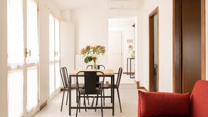 Un coin repas avec une table et des chaises, un vase rempli de fleurs et un canapé rouge.