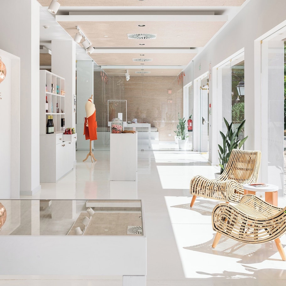 A modern hotel lobby with a glass wall, a reception desk, wicker chairs, and a potted plant.