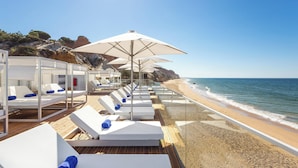 A beachside hotel with sun loungers, umbrellas, and a view of the ocean. - Pine Cliffs Ocean Suites, a Luxury Collection Resort & Spa (Albufeira)