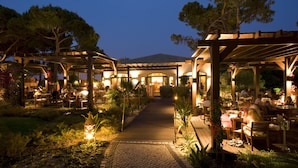 An outdoor dining area with tables and chairs, a pathway, and a pergola structure. - Pine Cliffs Ocean Suites, a Luxury Collection Resort & Spa (Albufeira)