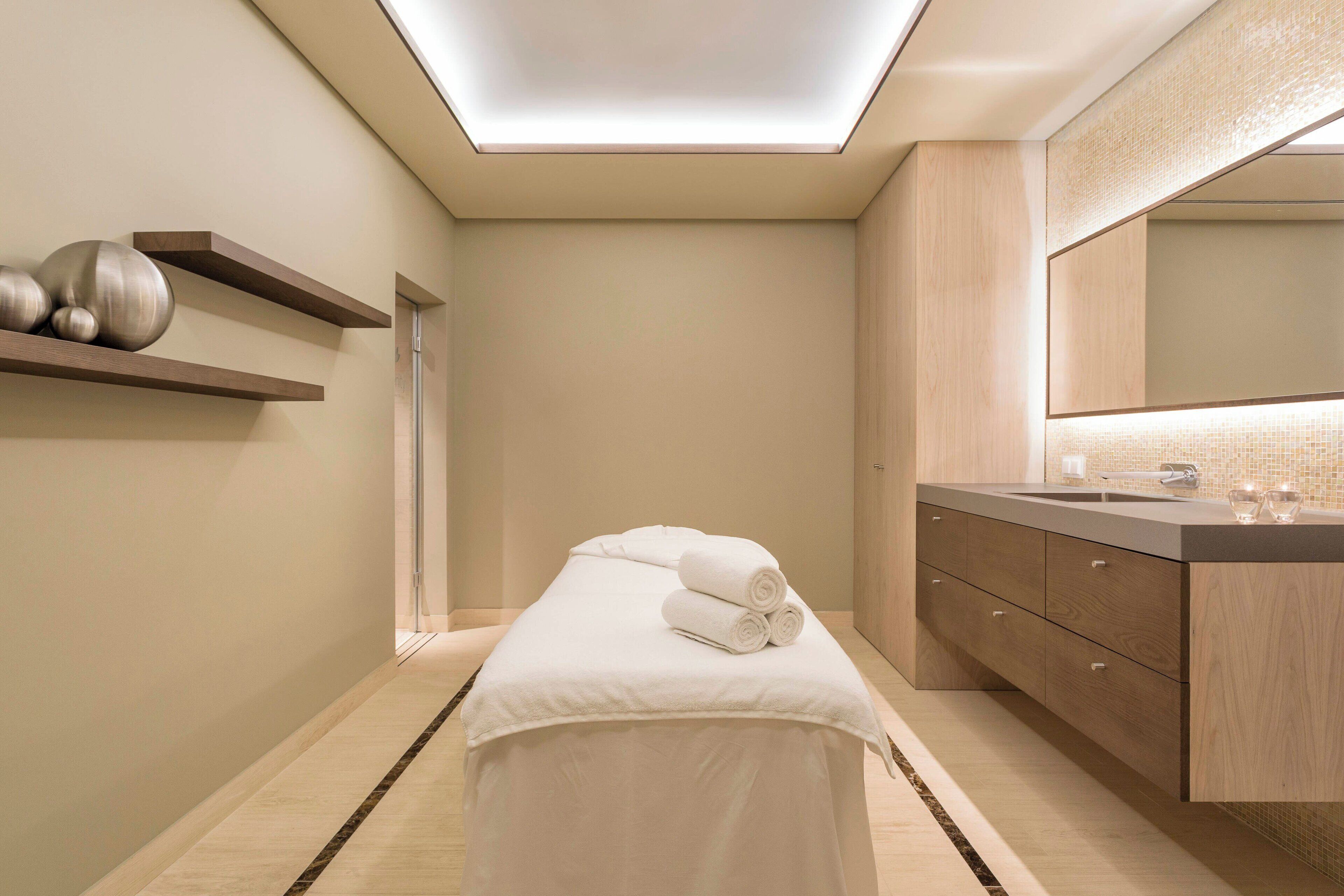 Un baño moderno con tragaluz, tocador de madera y mesa de masajes.