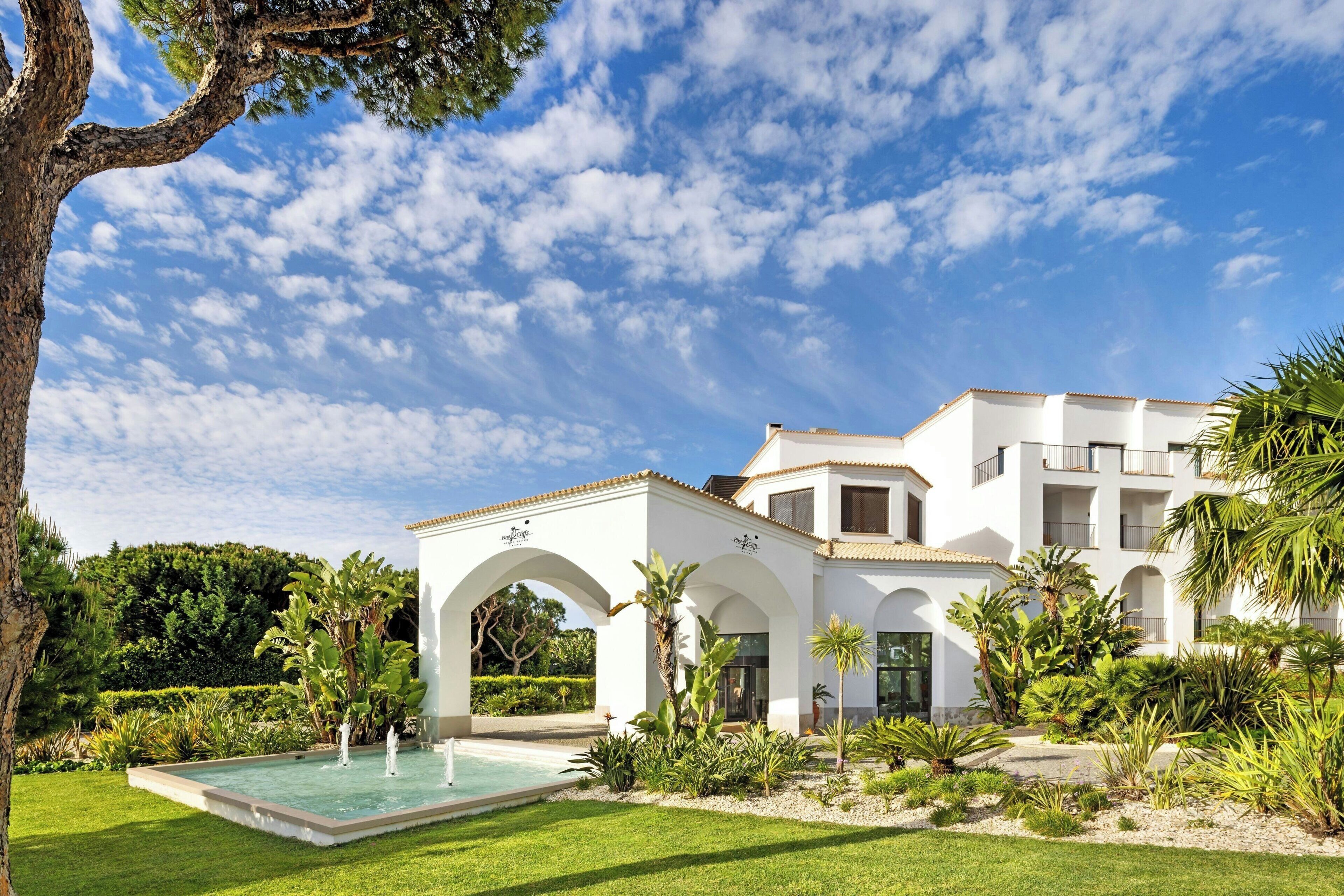 A white building with arched walkways and a swimming pool.