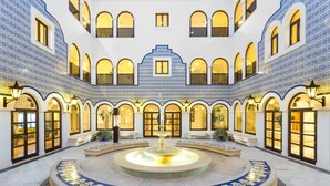 A courtyard with a central fountain, arched windows, and tiled walls. - Pine Cliffs Ocean Suites, a Luxury Collection Resort & Spa (Albufeira)