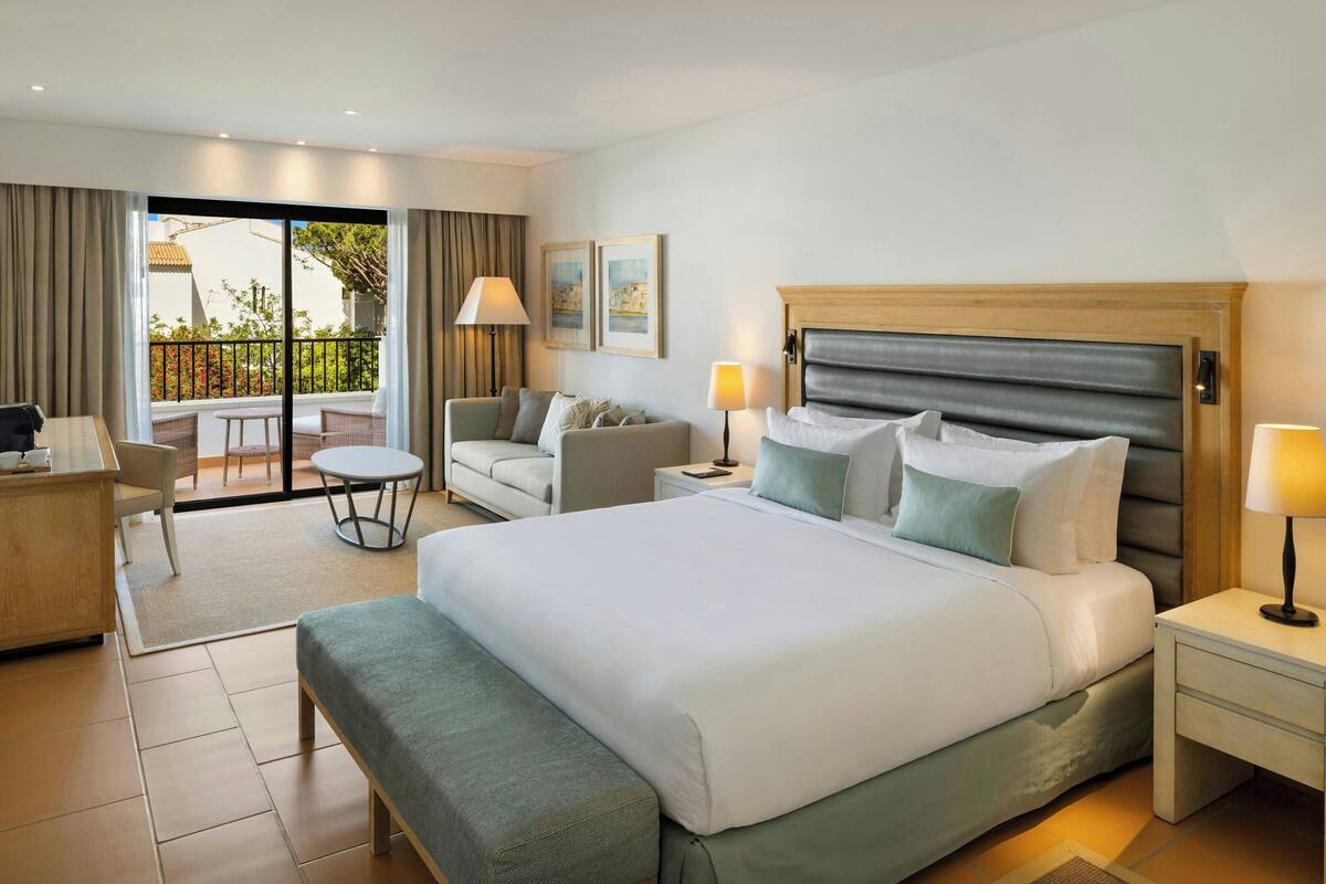 Une chambre d’hôtel avec un grand lit, un bureau, un canapé et un balcon donnant sur l’extérieur.