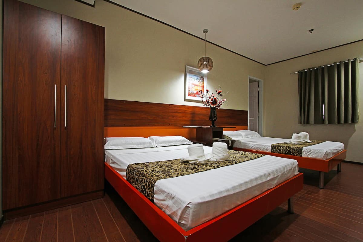 A hotel room with two beds, wooden wardrobe, and a painting on the wall.