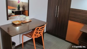Une pièce de taille modeste, comprenant un bureau en bois, une chaise, un miroir et une armoire.