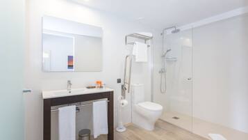 Ein modernes Badezimmer mit einer Duschkabine aus Glas, einer weißen Toilette und einem Waschtisch mit Spiegel und Waschbecken.