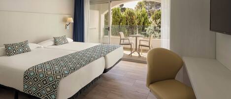 A hotel room with a bed, a desk, a chair, a TV, and a balcony with a table and chairs.