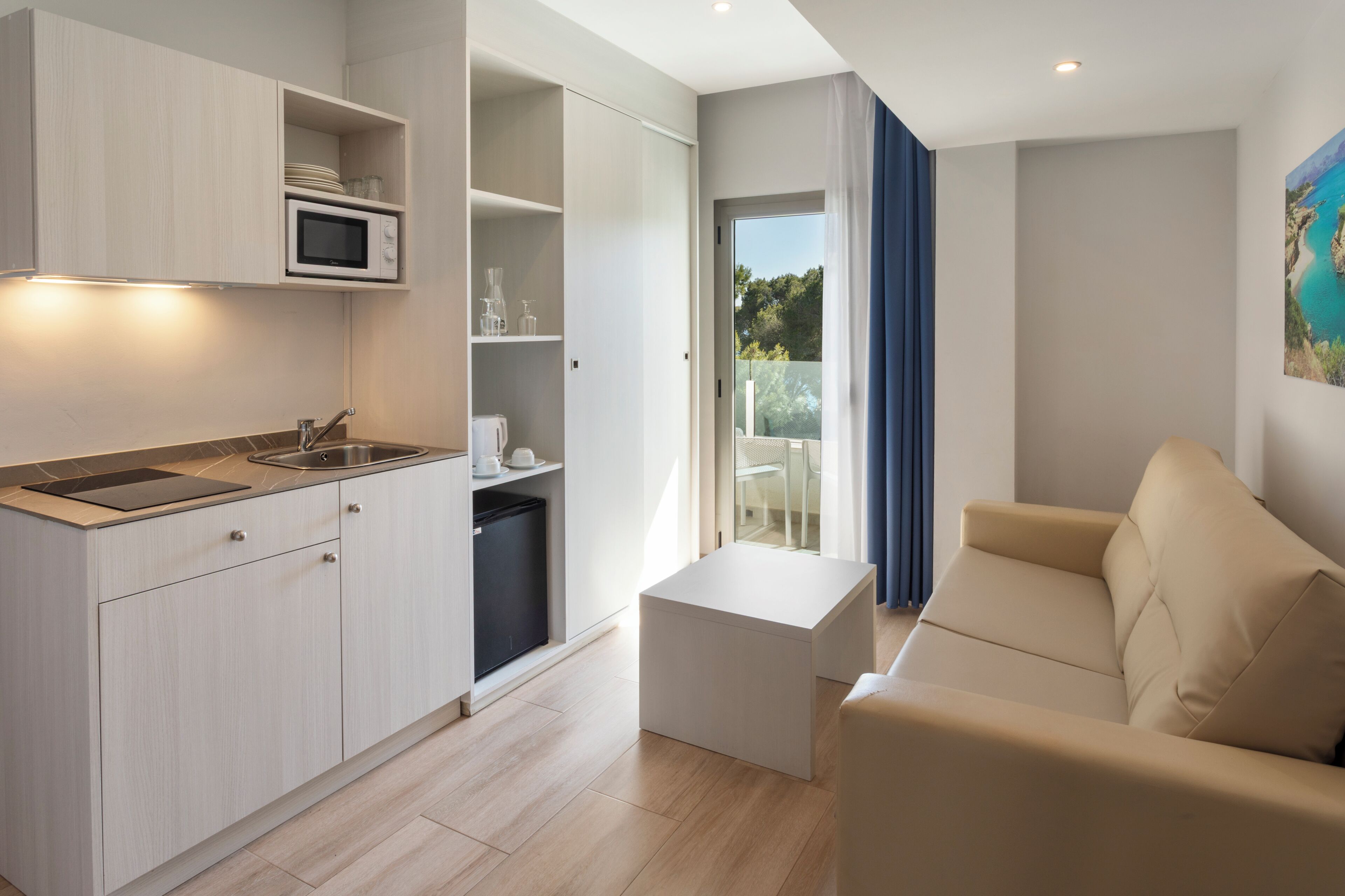 Una cocina moderna con electrodomésticos integrados, un comedor con sofá y vistas al exterior.