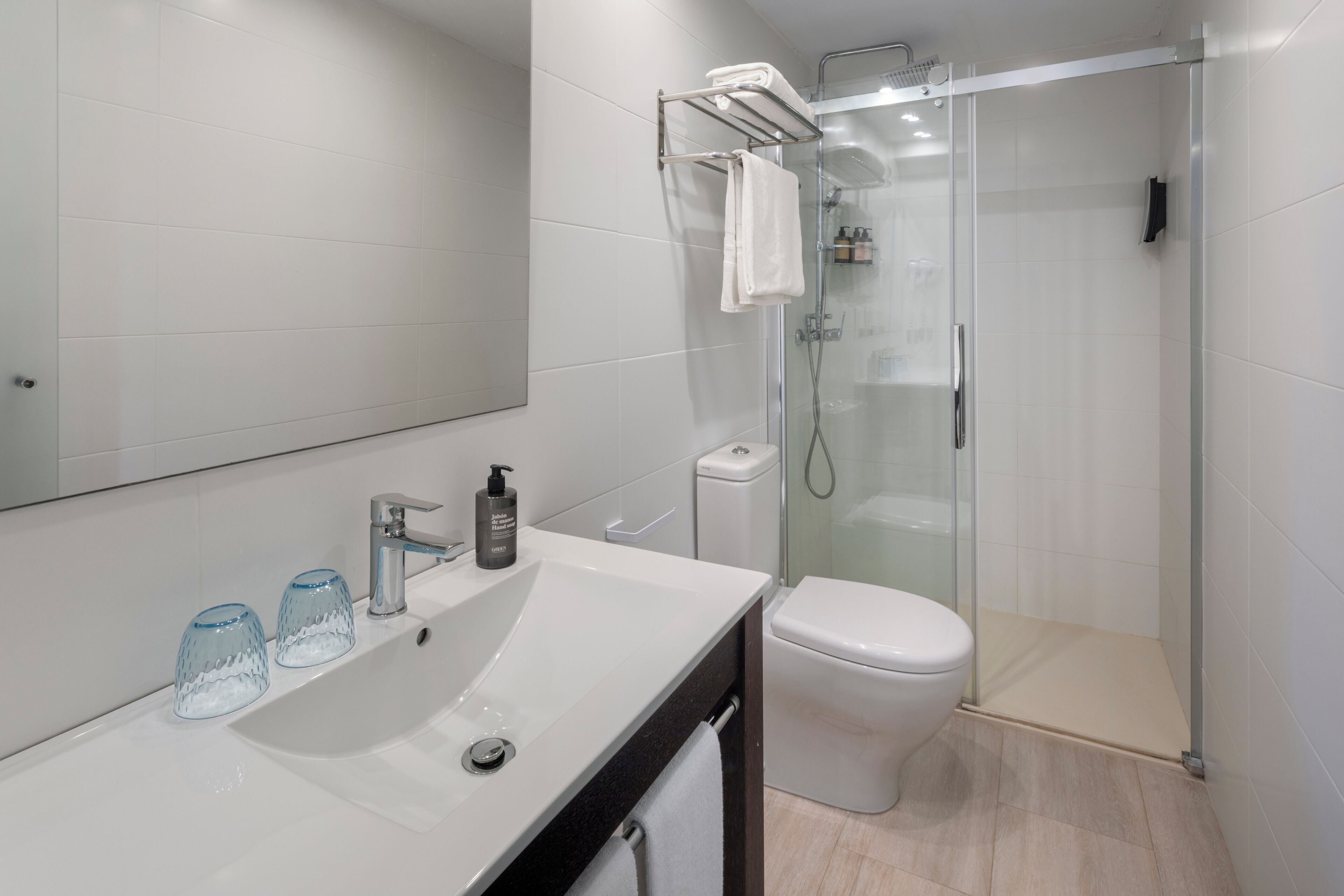 A modern bathroom with a white sink, a glass shower enclosure, and a toilet.