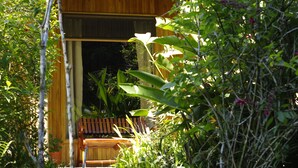 A wooden deck with a bench, surrounded by lush greenery and a wooden fence. - Hospedaje Mariposa (Monteverde)