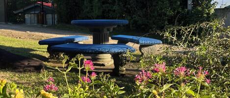 Ein Brunnen in einem Garten, im Hintergrund ein Gebäude.