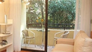 Ein Hotelzimmer mit Bett, Schreibtisch mit Lampe, Stuhl, kleinem Tisch mit Orangensaftgläser und Balkon mit Stühlen und Tisch.