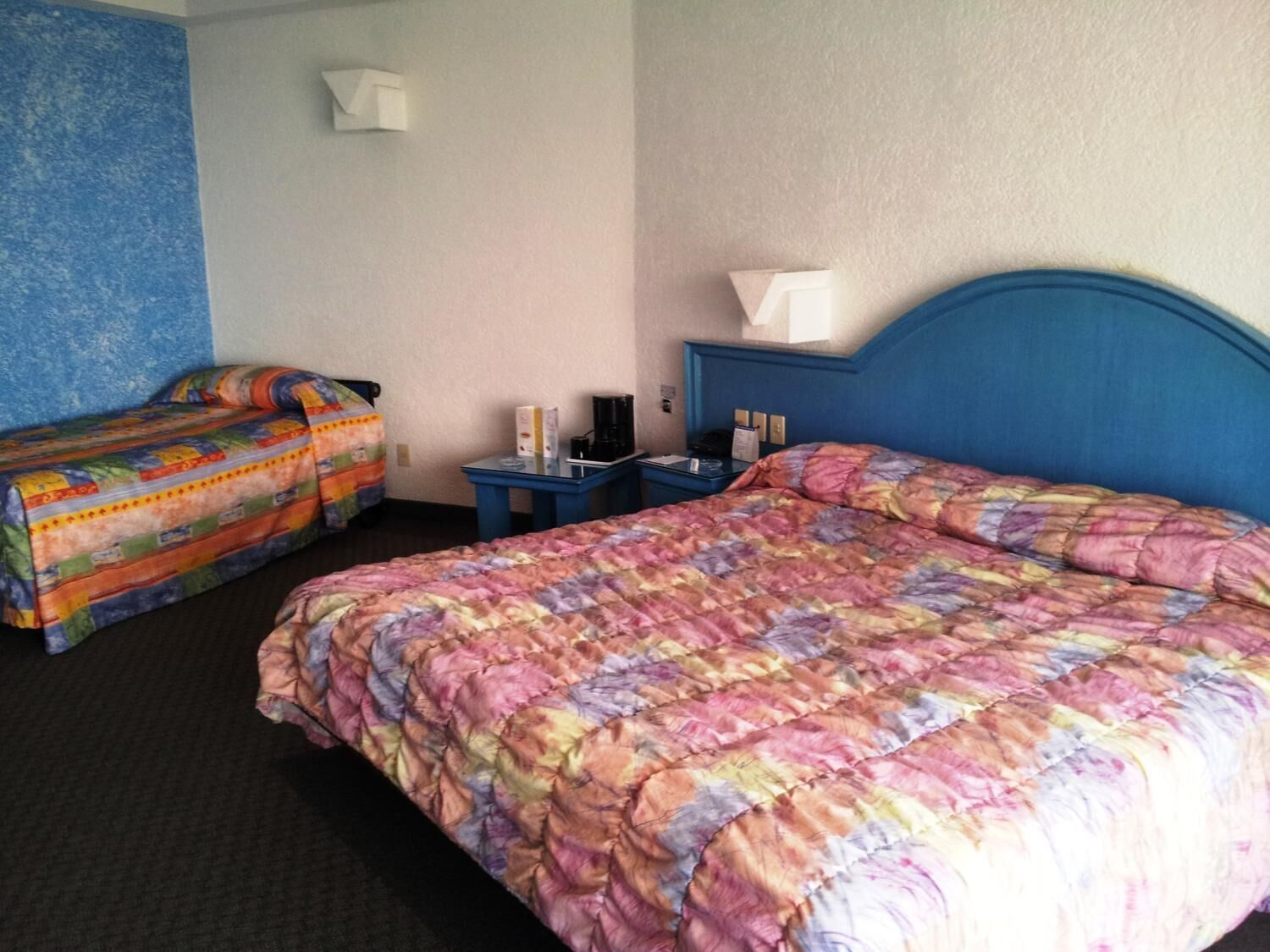 A hotel room with two beds, a desk, and a lamp.