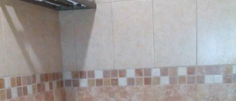 A bathroom with a toilet, a towel rack, and a showerhead.