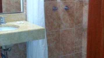 A bathroom with a shower, a sink, and a mirror.