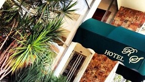 A hotel entrance with a green awning and a stone facade. - Hotel RS (Córdoba)