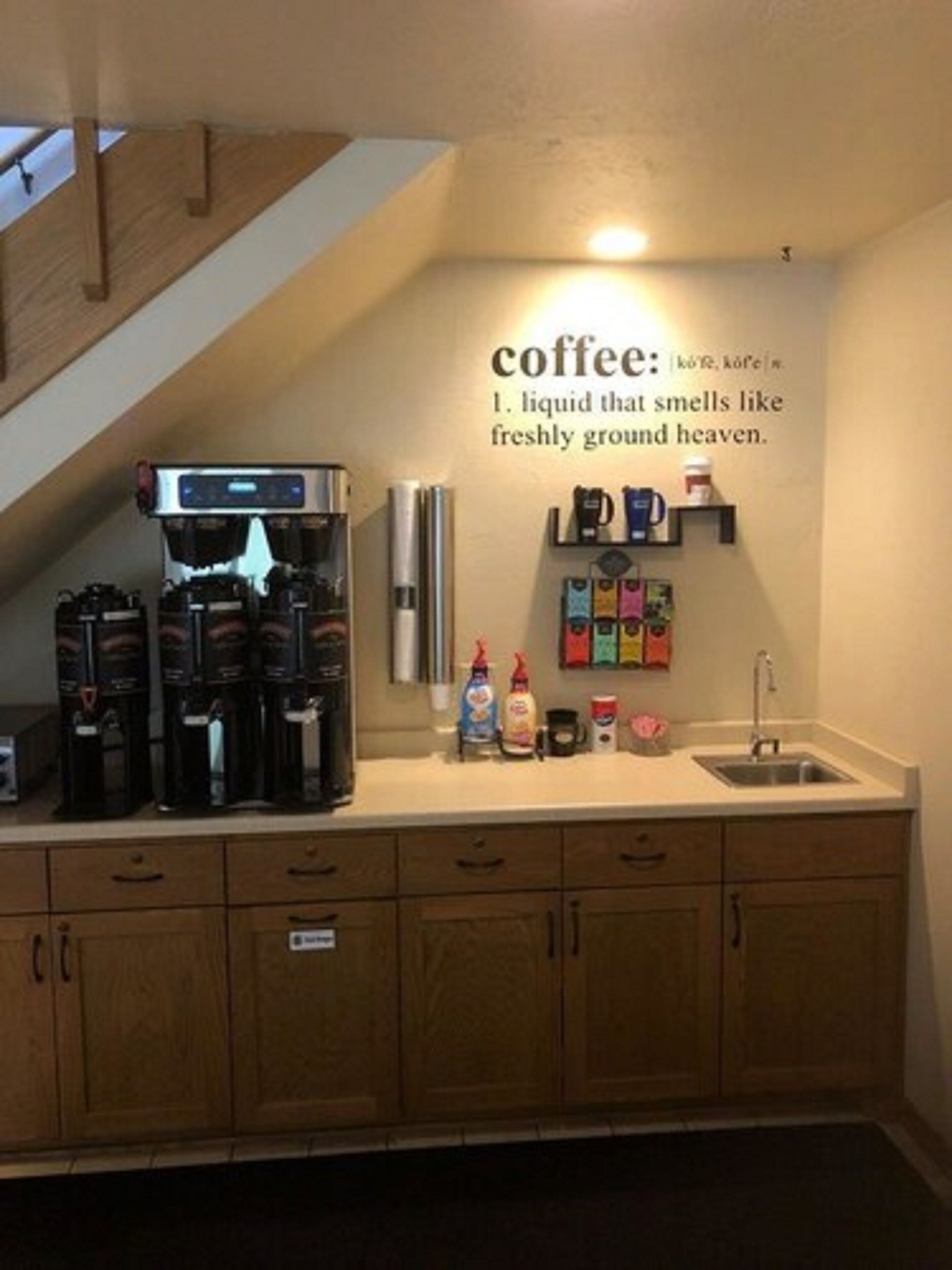 A kitchen with a coffee station, including a coffee machine, a kettle, and various coffee pods.