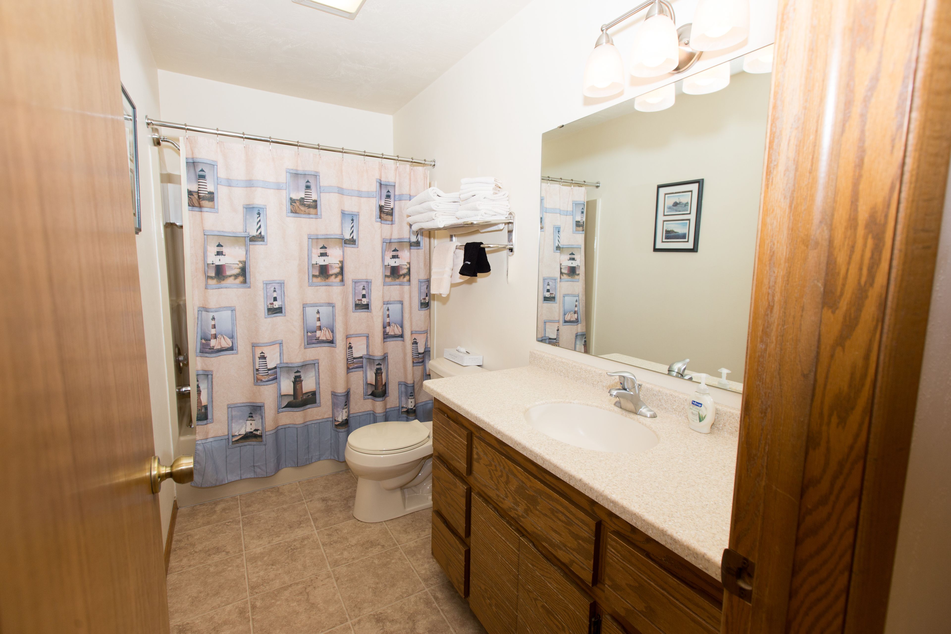 A bathroom with a toilet, sink, and wooden cabinets.