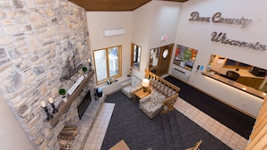 Un hall acogedor con pared de piedra, chimenea y mostrador de recepción.