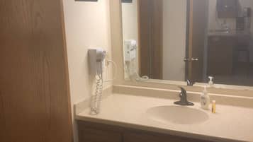 Une salle de bain avec un meuble-lavabo en bois, un évier, un miroir et un sèche-cheveux.