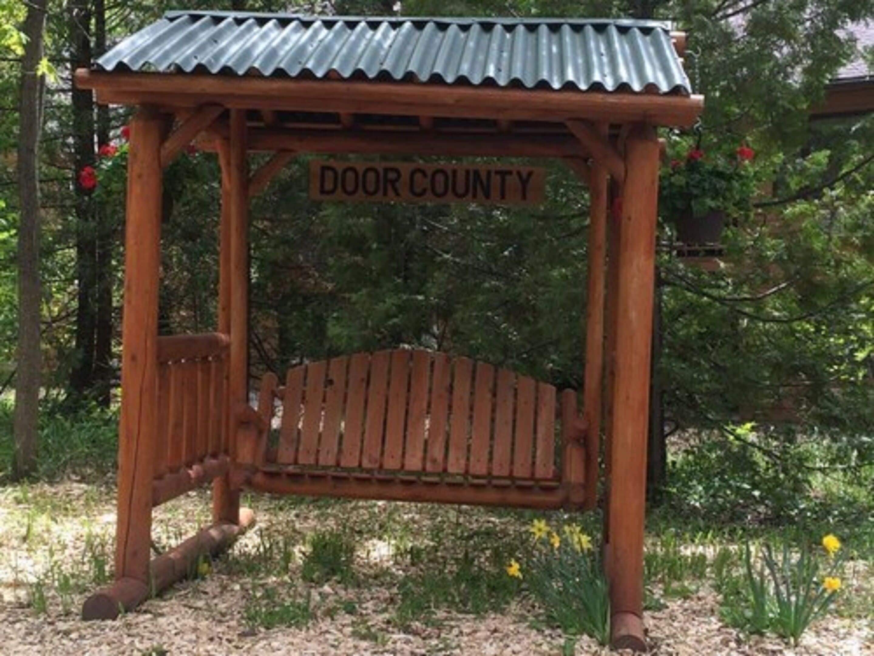 Une pergola en bois avec une enseigne indiquant « DOOR COUNTY », située dans un jardin.
