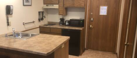 A compact kitchen with a sink, stove, microwave, and a small refrigerator.