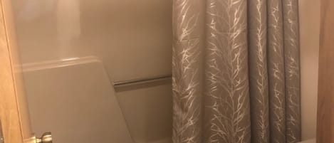 Un baño con ducha, inodoro y toallero.