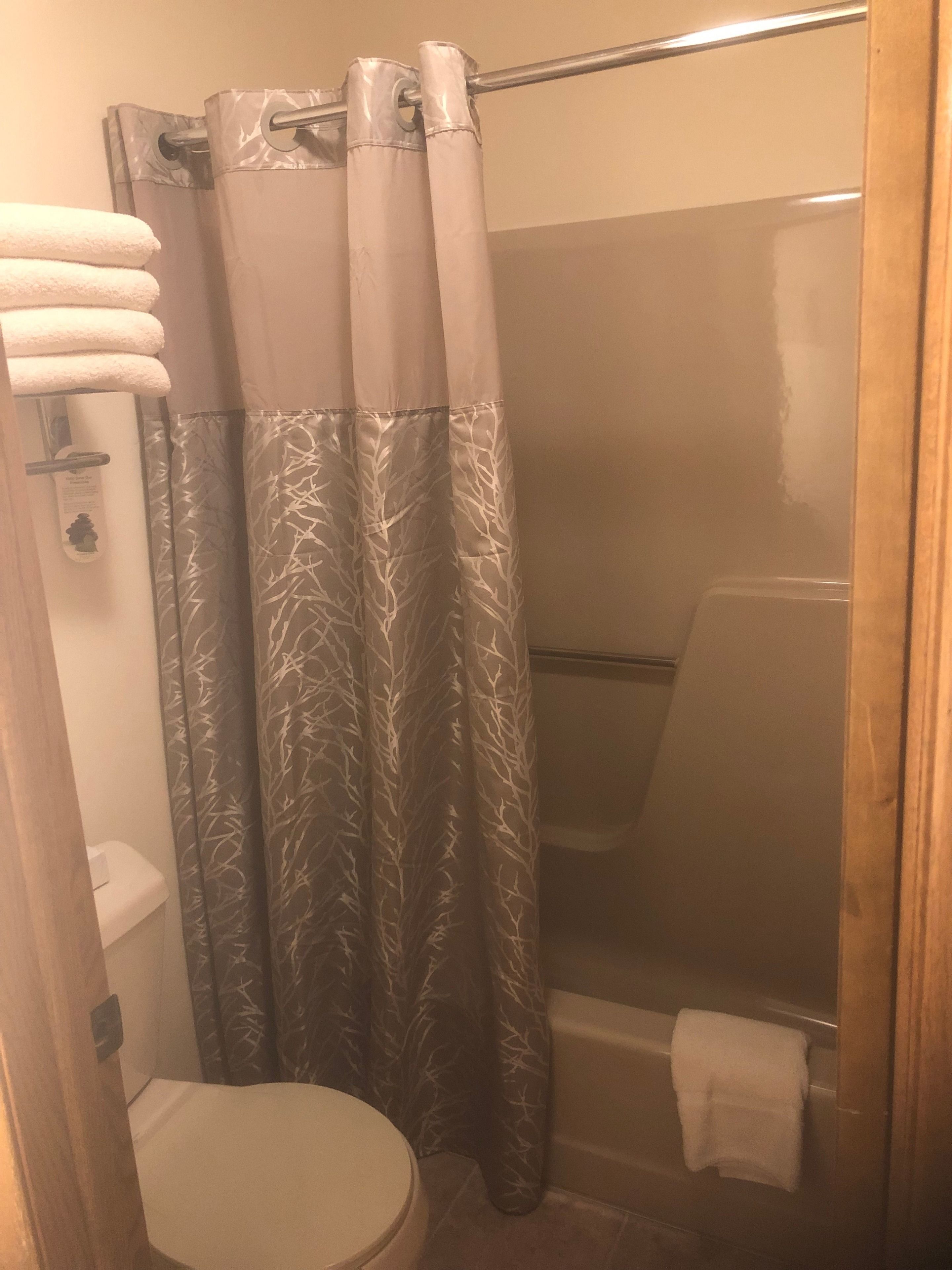 A bathroom with a shower curtain, a toilet, and a towel rack.