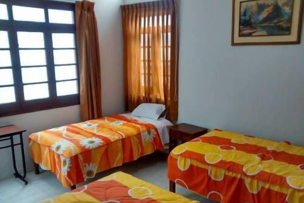 Una habitación con dos camas, un escritorio y un ventanal con cortinas.