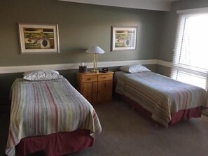 Una habitación con dos camas individuales, una mesita de noche con lámpara y dos cuadros en la pared.
