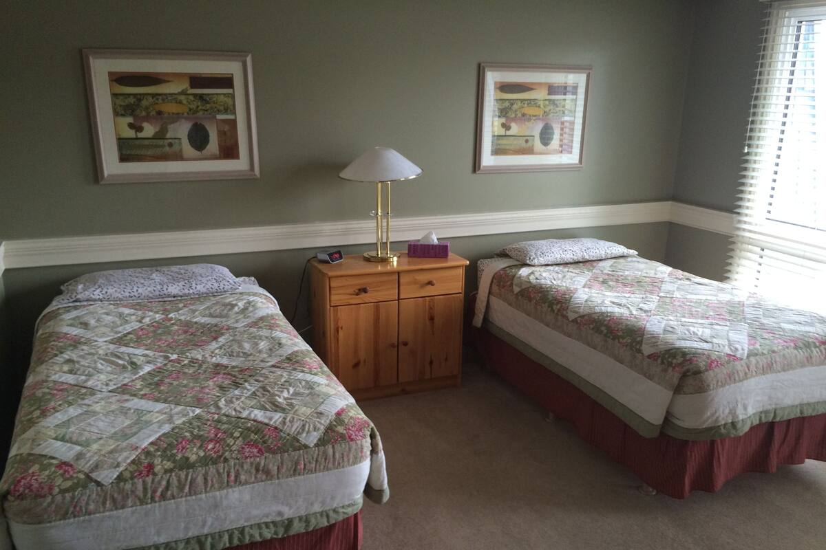 A bedroom with two beds, a nightstand, and two framed pictures on the wall.
