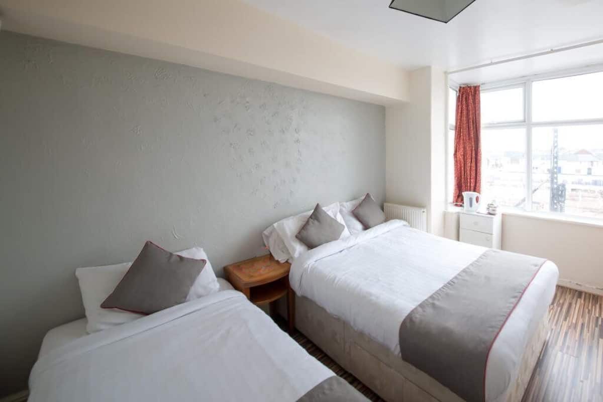 A hotel room with two beds, a window with a view, and a nightstand with a lamp.