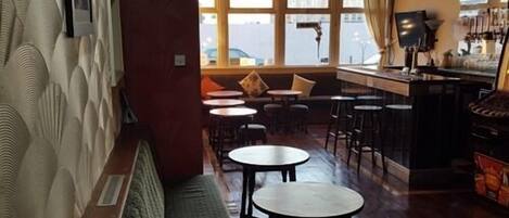 A cozy bar area with a long counter, multiple stools, and a bench seating area.