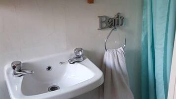 A bathroom with a white sink, a towel rack, and a shelf above the sink.