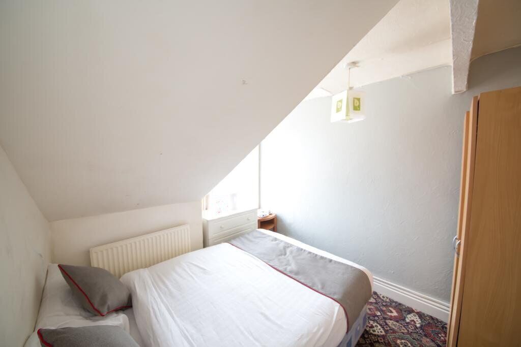A bedroom with a bed, a radiator, a window, and a door.