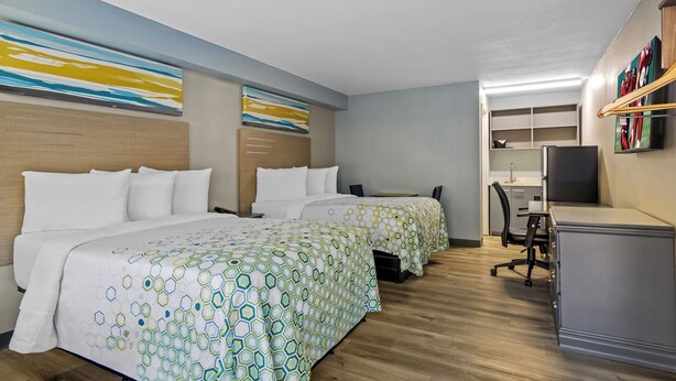 A hotel room with two beds, a desk, a chair, and a television. - HomeTowne Studios by Red Roof Athens, TN (Athens)