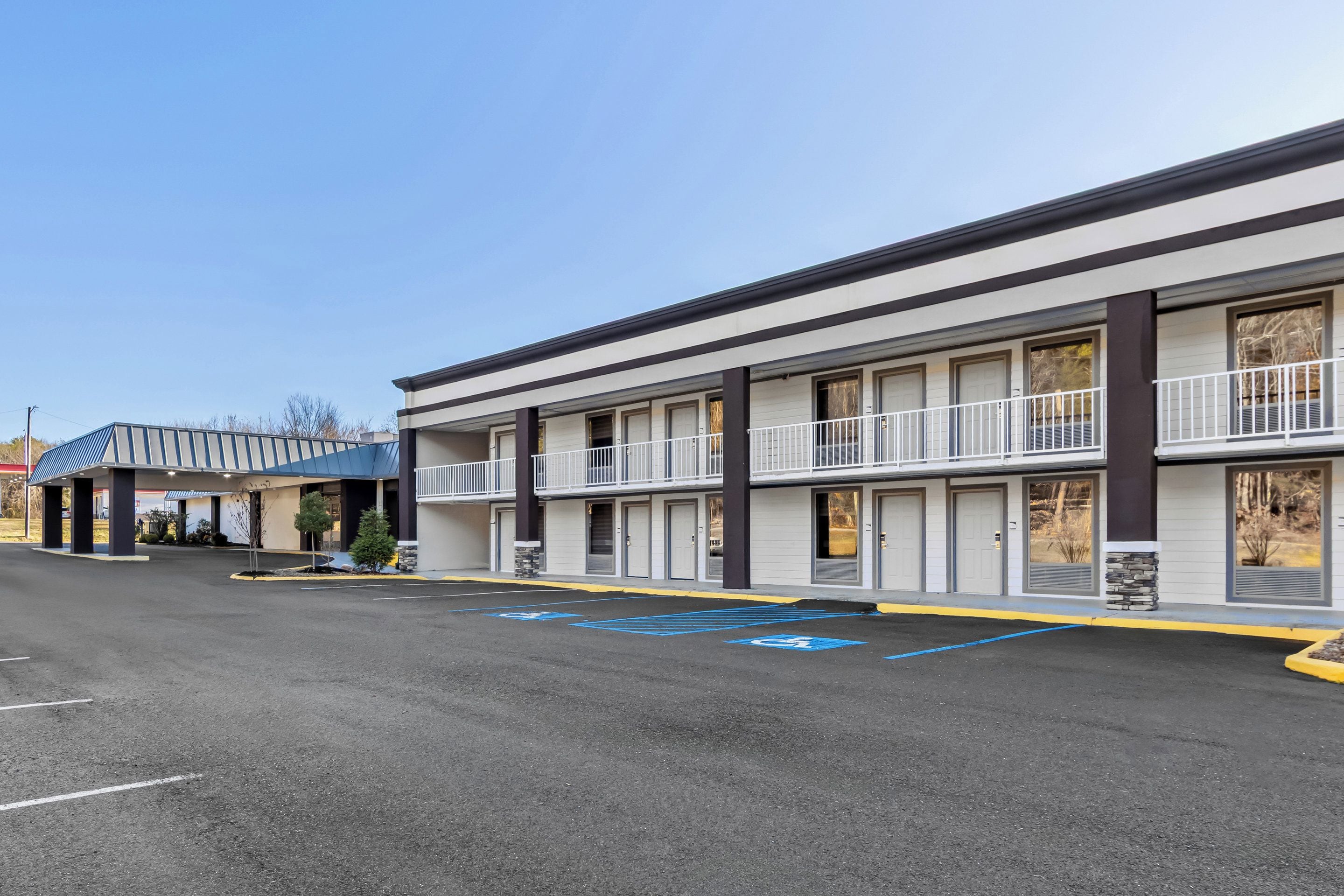 Un motel con varias habitaciones, un estacionamiento y un pequeño espacio al aire libre con plantas.