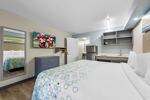 Habitación de hotel con una cama grande, un escritorio, un armario, un espejo y un televisor en la pared.