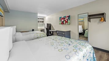 A hotel room with two beds, a desk, a chair, a wardrobe, and a mirror.