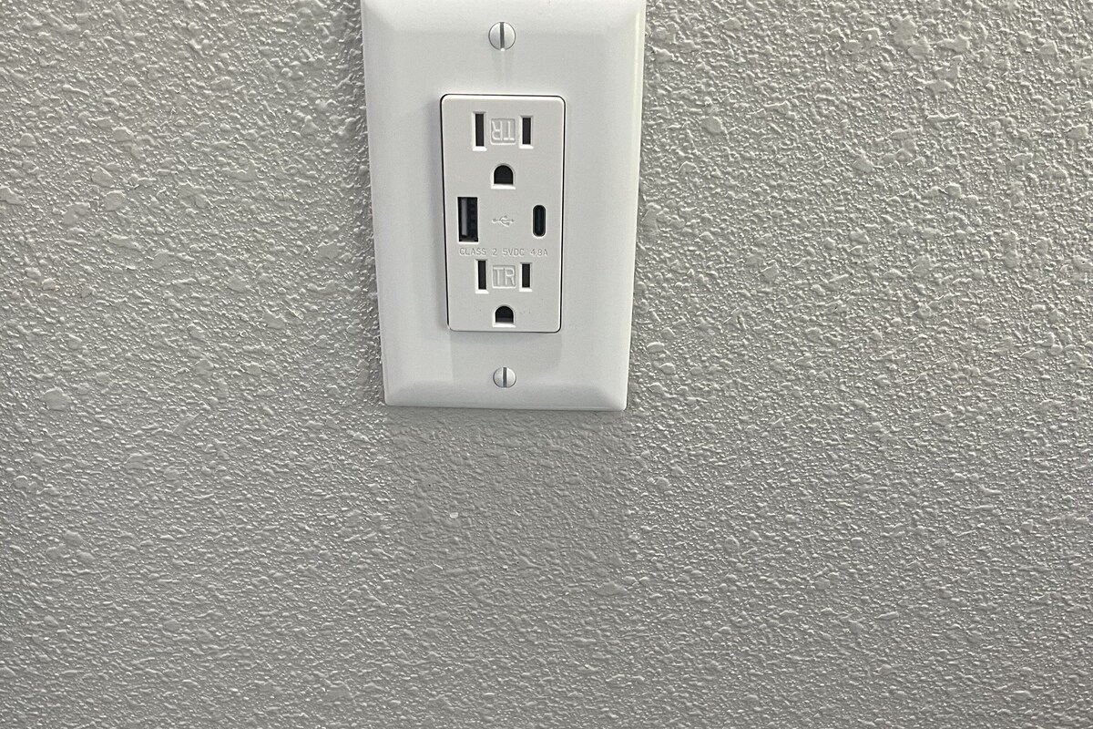A white electrical outlet on a textured wall.