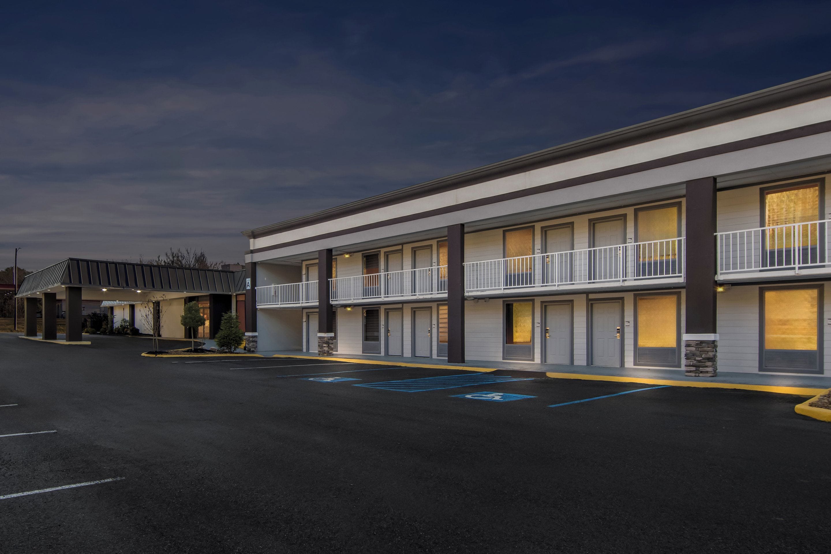 A modern hotel with a two-story structure, multiple rooms, and a parking lot with handicapped parking spaces.